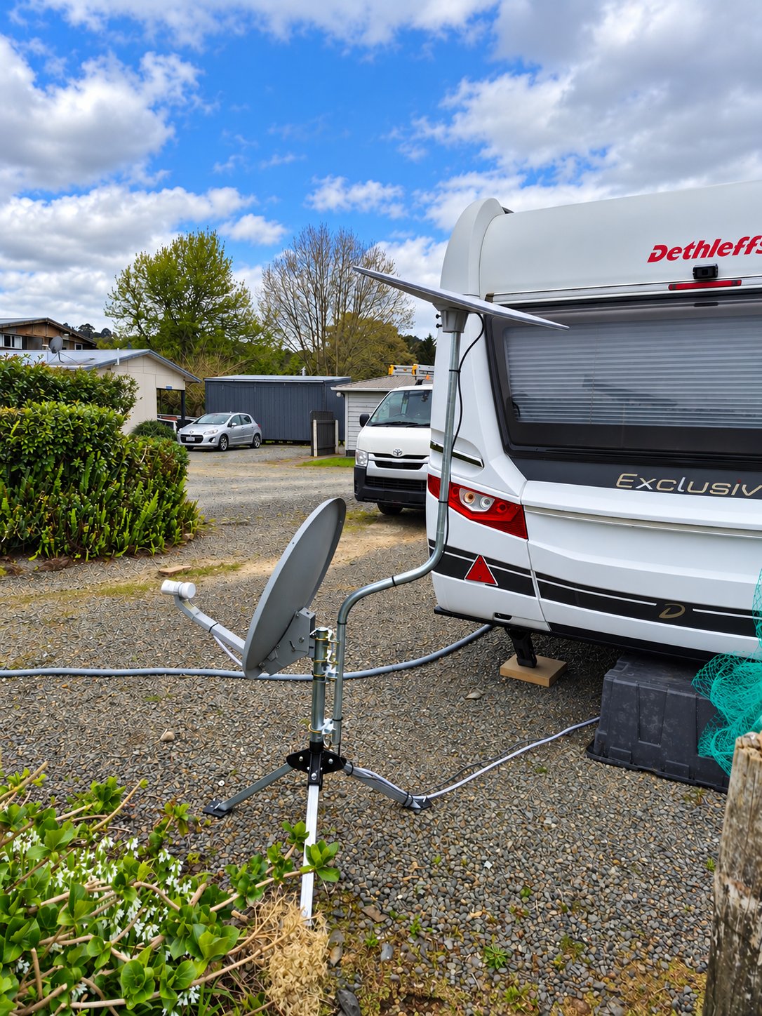 Starlink dish and Sky satellite dish set up beside a caravan at a caravan park, Whangarei