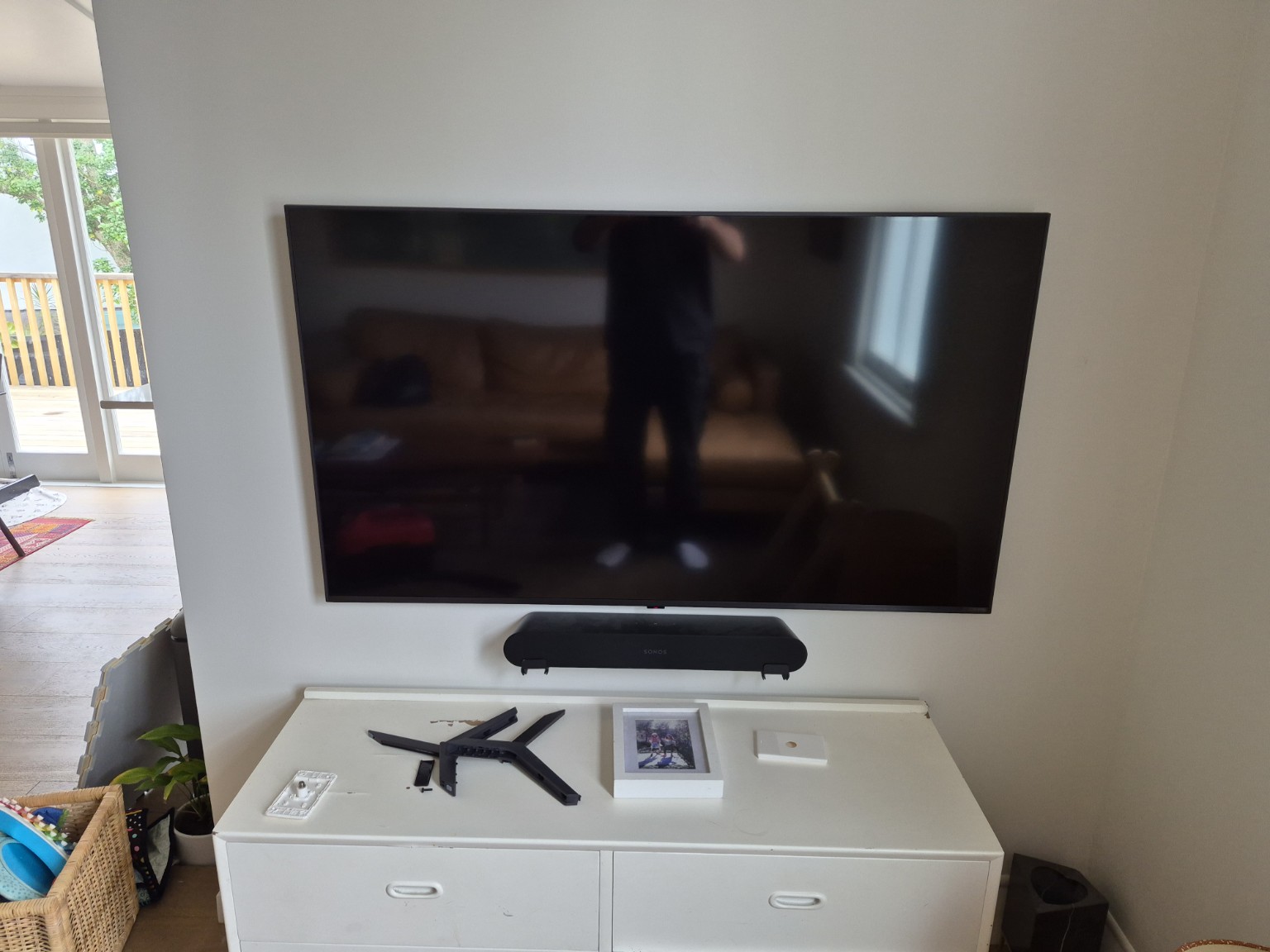 Wall-mounted TV with Sonos soundbar above a white media unit